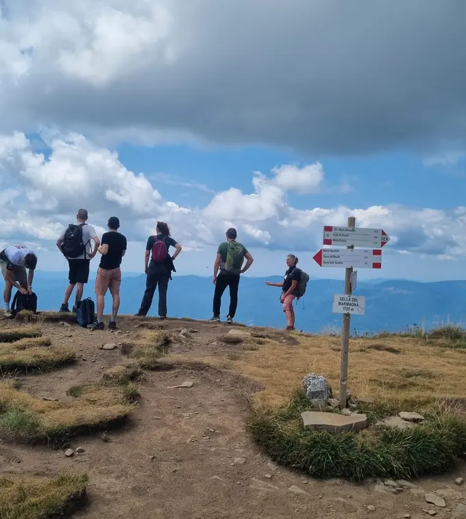 Un gruppo di persone guarda l'orizzonte dalla Sella del Marmagna, accanto ai cartelli dei sentieri