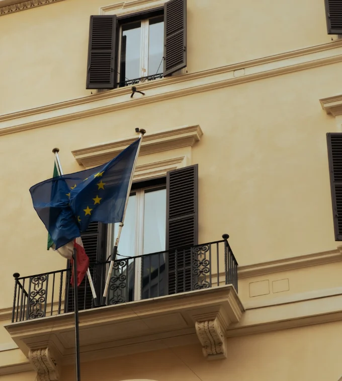 La facciata di un palazzo romano con le bandiere italiana ed europea su un balcone